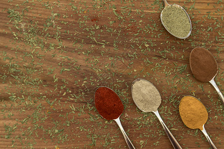 在勺子上安排各种彩色调味品木头美食金属芳香辣椒粉末烹饪种子桌子香气图片