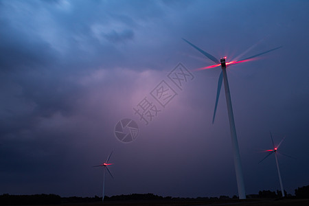 风力涡轮机在天空的阴暗蓝云上 风暴即将来临 风车有红色警告灯光涡轮太阳环境橙子电气海岸技术发电机力量戏剧性图片