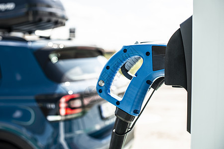 煤气站的电动汽车 蓝色汽车和加热电插头电气电缆充值机动性力量绿色能源引擎创新生态图片