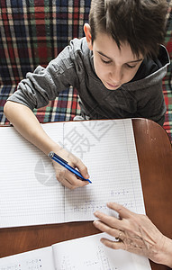 男孩做功课白色学习笔记本孩子们男生学生学校孩子桌子铅笔图片