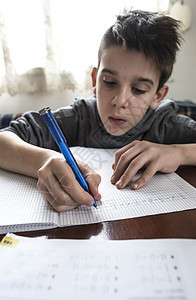 男孩做功课白色桌子写作学生学校青年房间男生铅笔童年图片