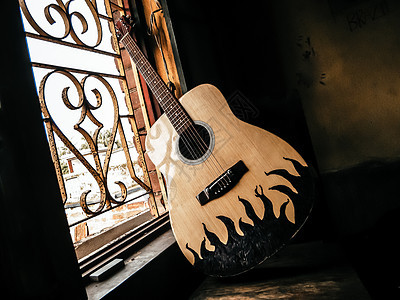 一把音响吉他放在古老的窗户旁边 阳光柔软 来自怀旧的吉他和弦 夏季旋律背景 近距离接近图片