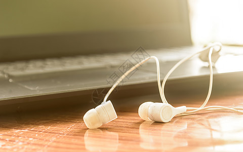 用于在便携式设备上收听音乐和声音的耳机 耳塞插孔 特写 背景上的笔记本电脑显示器 物联网 技术在现代工作场所的概念 选择性的焦点图片