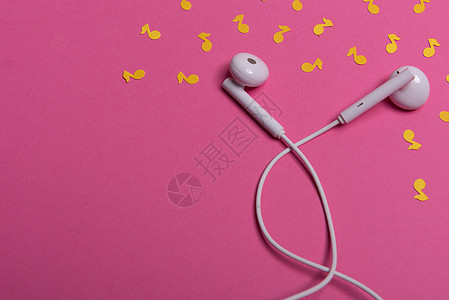 粉红色背景上的白色耳机和黄色纸币 从上面看立体声粉色创造力配饰电子文化技术笔记耳朵水平图片