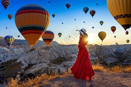 美丽的女孩站在土耳其的卡帕多西亚 寻找热气球旅游女士游客享受阳光远足日落空气自由假期图片