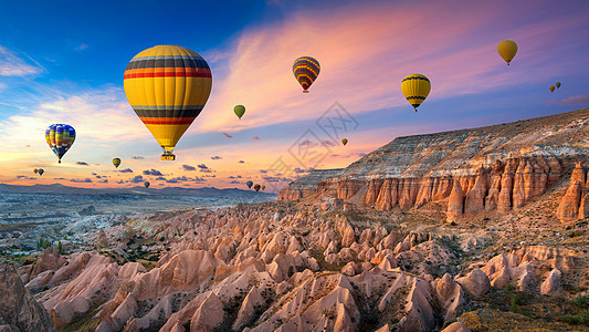 热气球和红谷日落时在土耳其卡帕多西亚的戈雷梅冒险火鸡烟囱岩石洞穴石头日落自由航班天空背景图片