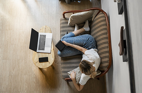 女人躺在沙发上 一边使用笔记本电脑一边休息 一边使用 ae 阅读器 在线学习和工作 自由职业者 女孩正在用她放在沙发上的笔记本工图片