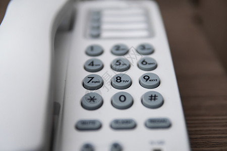 在酒店的棕色桌子上有灰色蝙蝠棒的白色旧电话乡愁古董数字服务拨号中心塑料电讯热线讲话图片