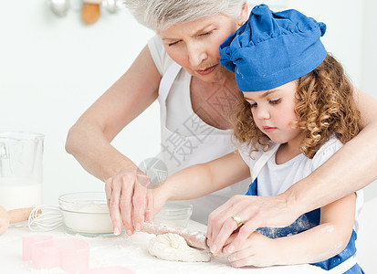 一个小女孩和她奶奶一起烘烤的毛巾青年面包别针幸福女性爱好家庭饼干姐姐图片