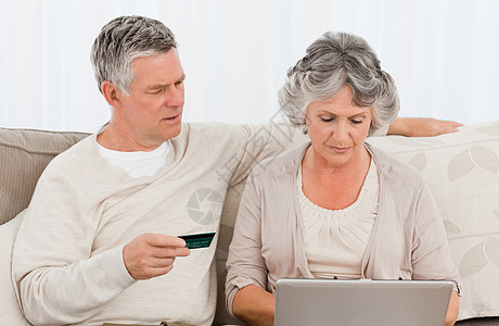 老年人在互联网上买东西保险男人财产信用卡妻子电脑中年不动产丈夫沙发背景图片