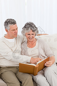 老年夫妇在看相片专辑男人夫妻女士保险房间丈夫中年照片沙发妻子图片