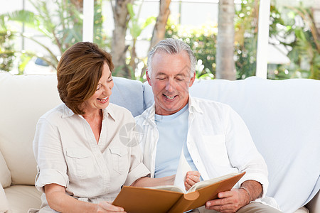 年长者在家里看相片专辑不动产夫妻老年妻子微笑保险中年男人家具沙发图片