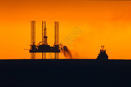 日落时用燃烧的火炬筑起石油平台 在港口钻井平台上倾斜钻头拖船勘探钻孔燃料力量活力船运机器交通图片