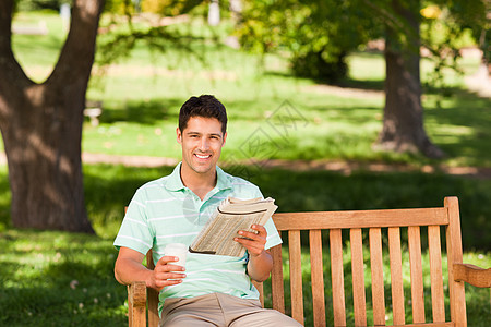 男人与报纸公园绿色花园长椅咖啡幸福杯子闲暇游戏填字图片