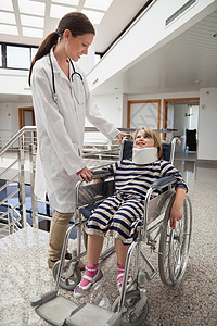 女医生对坐在轮椅和颈部支架上的儿童微笑的女医生图片