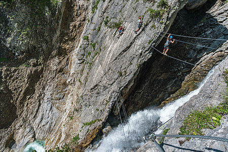 奥地利瀑布边的Via ferrata乐趣悬崖运动员运动攀岩天空顶峰登山者爱好头盔图片