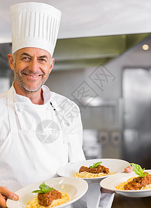 自信的男厨师 厨房有熟饭菜男性白人工作围裙制服帽子食物餐厅熟食盘子图片