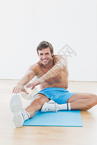 运动男子在健身工作室伸出手脚伸腿护理训练活动调子灵活性竞技健身室短裤身体地面图片