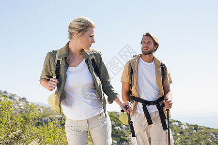 有吸引力的徒步旅行夫妇在山上行走微笑男性远足勘探农村地形荒野冒险家晴天登山杖图片