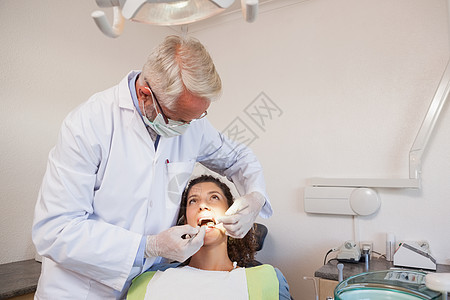 牙科医生检查牙医椅子上的病人牙齒口镜斜角镜设备手术男人医学口腔科工作牙科保健员图片
