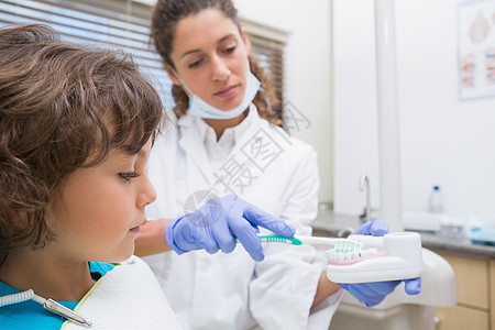 小儿科牙医 向小男孩展示如何刷牙学习围兜牙科考试健康专业职业打扫教学例行图片