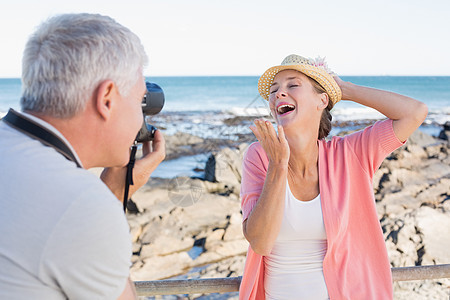 快乐的闲人 在海边拍拍伴侣的照片阳光金发男性摄影假期码头男人休闲女性微笑背景图片