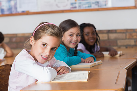 在课桌旁看书的可爱学生童年小学教育女性女孩班级黑色小学生同学们混血图片