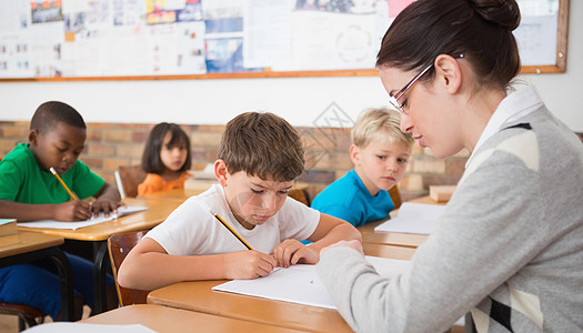 在课堂桌上写字的可爱学生女性老师学校童年职业早教男性知识同学们班级图片