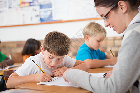 在课堂桌上写字的可爱学生瞳孔女性早教学校小学快乐同学们职业女孩帮助图片