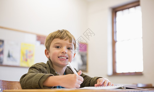 快乐的学生在书桌上写笔记本小学生学习幼儿园记事本早教写作课堂男生班级童年图片