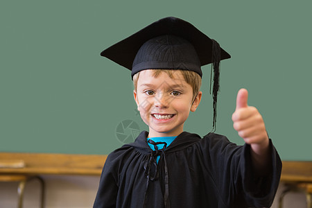 穿着毕业长袍的可爱学生在课堂上对着相机微笑快乐小学教育班级手势知识男性幼儿园黑板童年图片