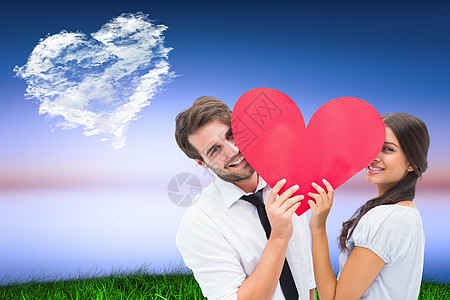一对情侣在镜头前微笑的复合图像 握着一颗心衬衫场地快乐沥青亲密感情怀日落混血男性情感图片