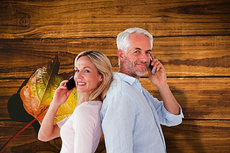 幸福的情侣用智能手机聊天的复合图像木板呼唤叶子休闲头发环境服装木头男性亲密感图片