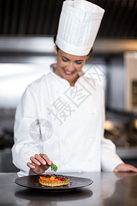 快乐的女厨师因食物而充饥工作厨师长制服盘子桌子职业饮食厨房微笑甜点图片