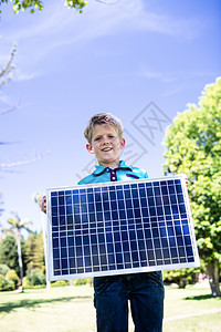 男孩拿着太阳能电池板公园晴天快乐休闲发电绿地能源童年草地男性图片