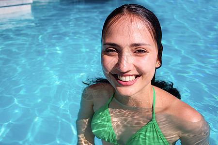 在游泳池里微笑的女人的肖像享受日光浴房子女士沙滩别墅假期泳装阳光水池图片