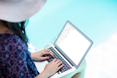 妇女使用她的笔记本电脑水池假期女士微笑家庭别墅闲暇阳光蓝色游泳池图片