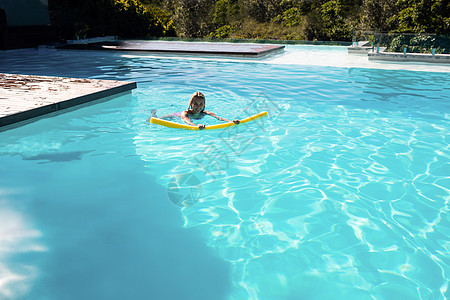 在游泳池中游泳的妇女阳光女性享受泳装晴天房子池面假期水池别墅图片