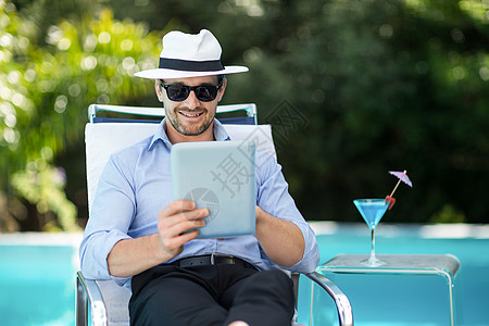智能人使用靠近游泳池的数码石板晴天电脑帽子娱乐假期触摸屏人士温泉互联网酒杯图片