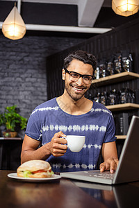 男人用笔记本电脑喝咖啡闲暇咖啡食品时间店铺饮料桌子面包眼镜男性图片