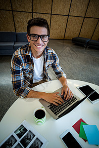 在办公桌工作的年轻人咖啡手机快乐男性平板咖啡杯互联网便利贴沟通微笑图片