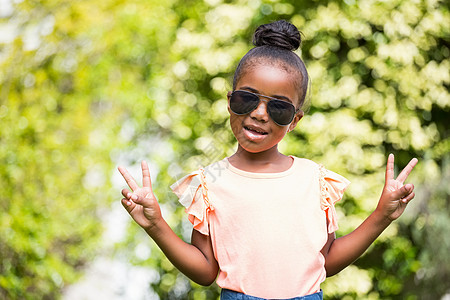 在公园戴墨镜的小女孩黑发和平绿色女性牛仔裤喜悦快乐黑色女孩享受图片