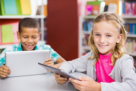在图书馆使用数字版的孩子们学习女性男性技术桌子微笑快乐童年头发触摸屏图片