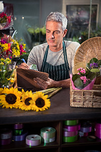 在剪贴板上写字的男花匠花艺清单花朵失速命令写作服务桌子盆栽职业图片