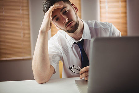 坐在办公室的疲劳男子人士职业悲伤男性工作商业商务沟通眼镜挫折图片