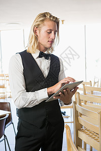 餐饮中使用数字平板电脑的服务员互联网马甲制服滚动工人男性食品网络技术酒店图片