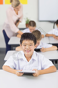 使用数字平板电脑对男学生的肖像孩子享受感情触摸屏制服沟通教育网络女孩小学图片