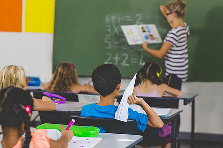 有纸机的男孩 老师在课堂上教书学习桌子混血教学男生女学生学校孩子们女孩小学图片