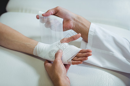 在病人受伤的手上贴绷带的心理治疗师纱布脊椎服务诊所伤害包扎疼痛医疗职业从业者图片