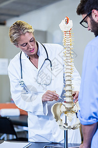 向病人解释脊椎模型的理疗师咨询生理学治疗职业女士医学健身疗法保健医院图片